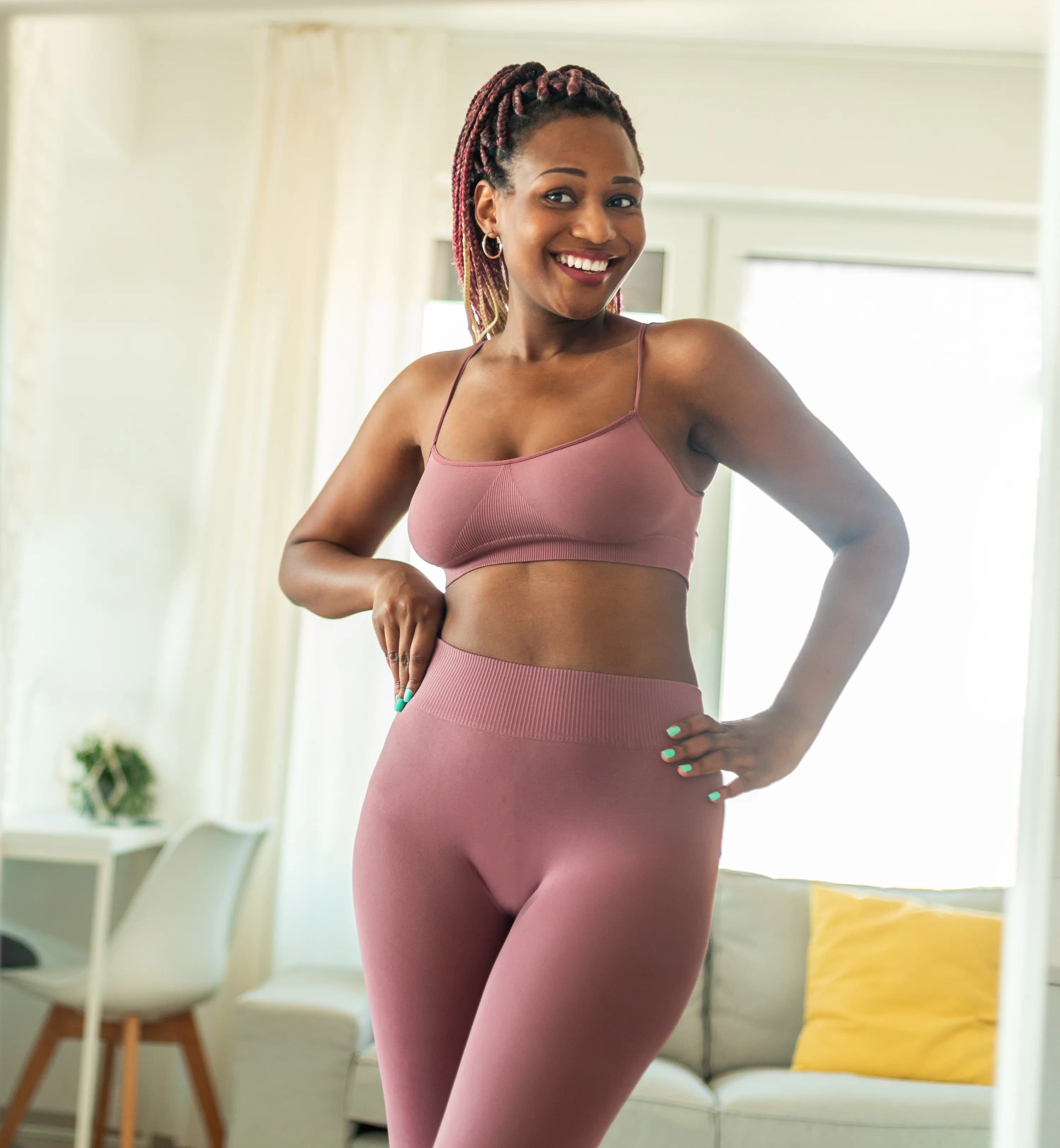 A woman in activewear standing and smiling at home